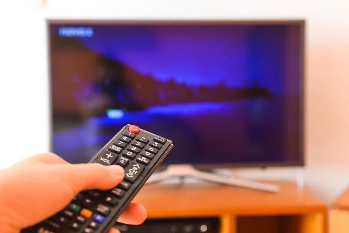TV 화면을 향해 리모컨을 든 손